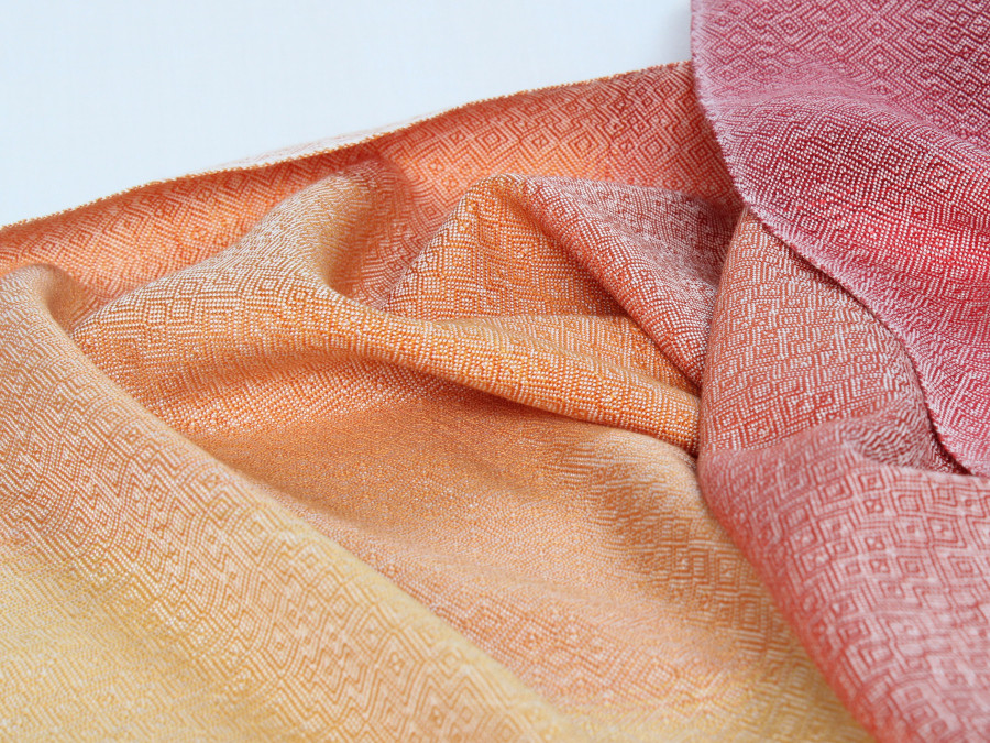 Close-up of shiny yellow-orange-red fabric with small irregular diamond patterns in white, forming satisfying waves.